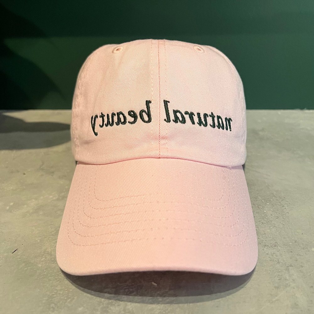 Pink pigment-dyed 6 panel cap with "natural beauty" embroidered and mirrored on the front