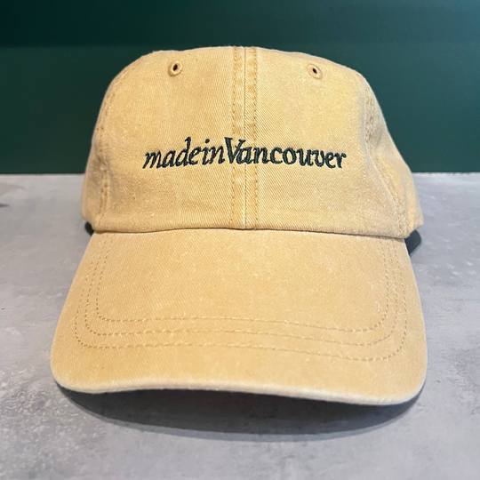Front view of mustard pigment dyed 6-panel cap with 'made in Vancouver' embroidered text.