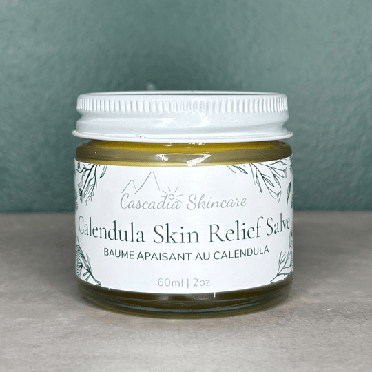 Calendula Skin Relief Salve on a grey countertop and green background