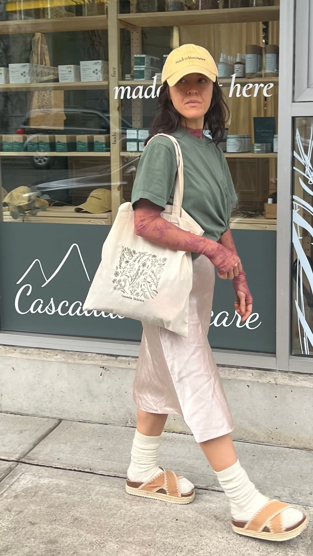 Woman walking outside the Cascadia Skincare store with the Cascadia Floral Embroidery tote bag.
