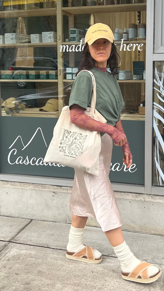 Woman walking outside the Cascadia Skincare store with the Cascadia Floral Embroidery tote bag.