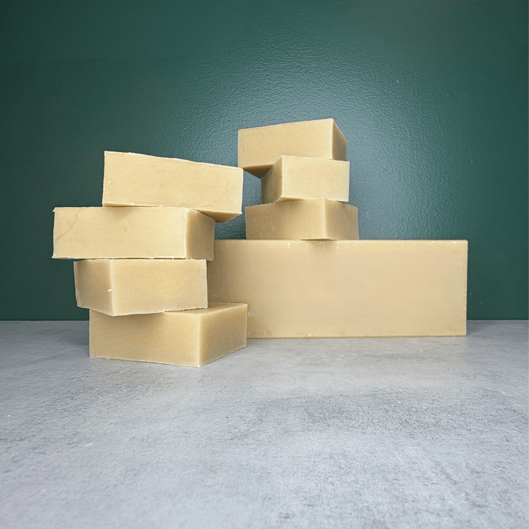 Goat Milk Soap Bars and Bulk Bar shown on a grey countertop and green background.