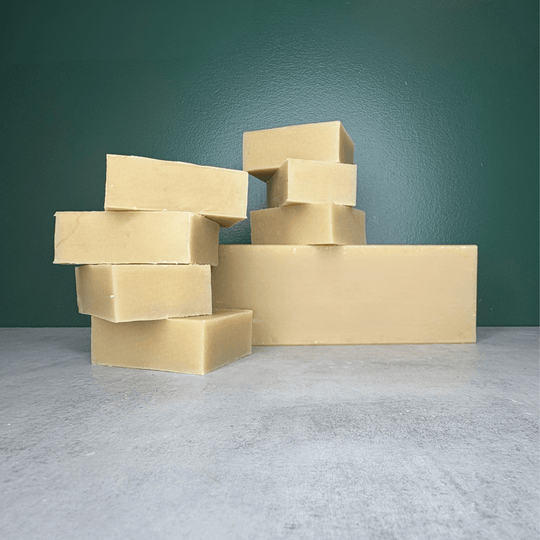 Goat Milk Soap Bars and Bulk Bar shown on a grey countertop and green background.