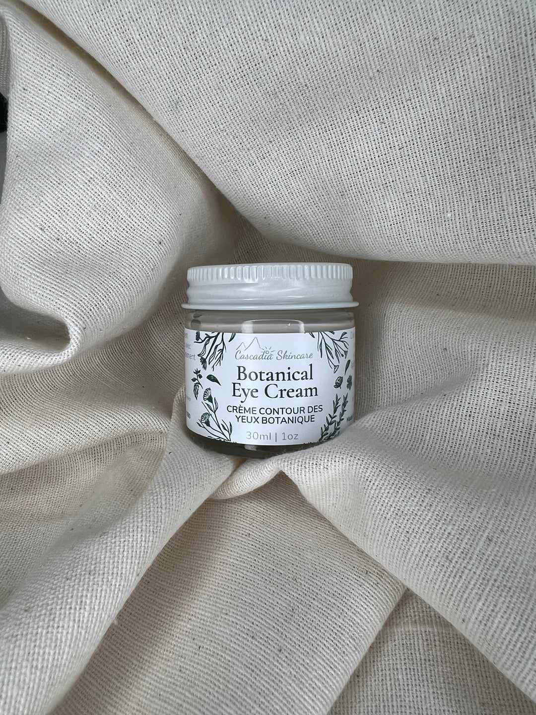 Jar of Botanical Eye Cream on a textured fabric background