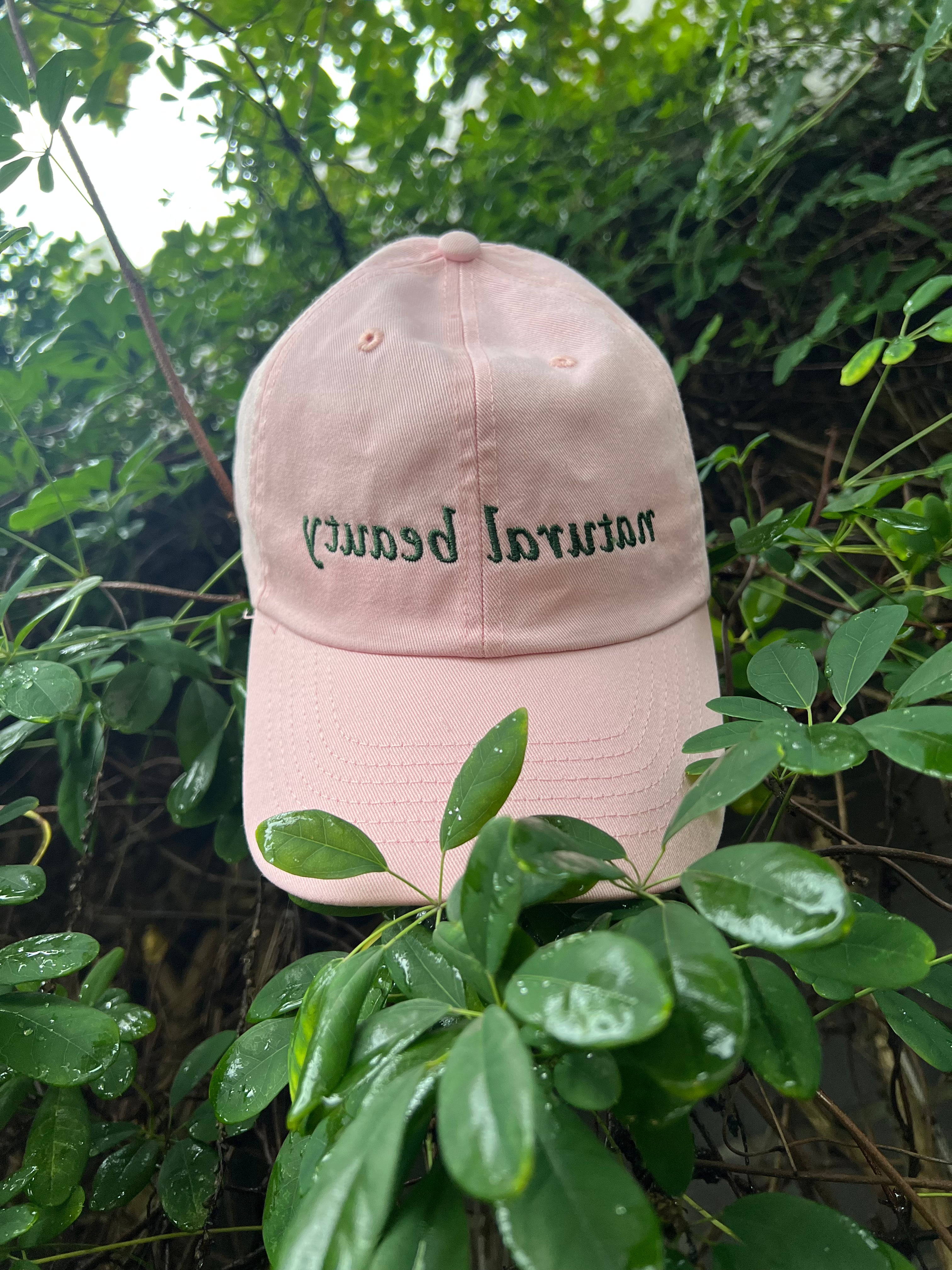 Pink cotton twill baseball cap with "natural beauty" embroidered in green, mirrored, on the front